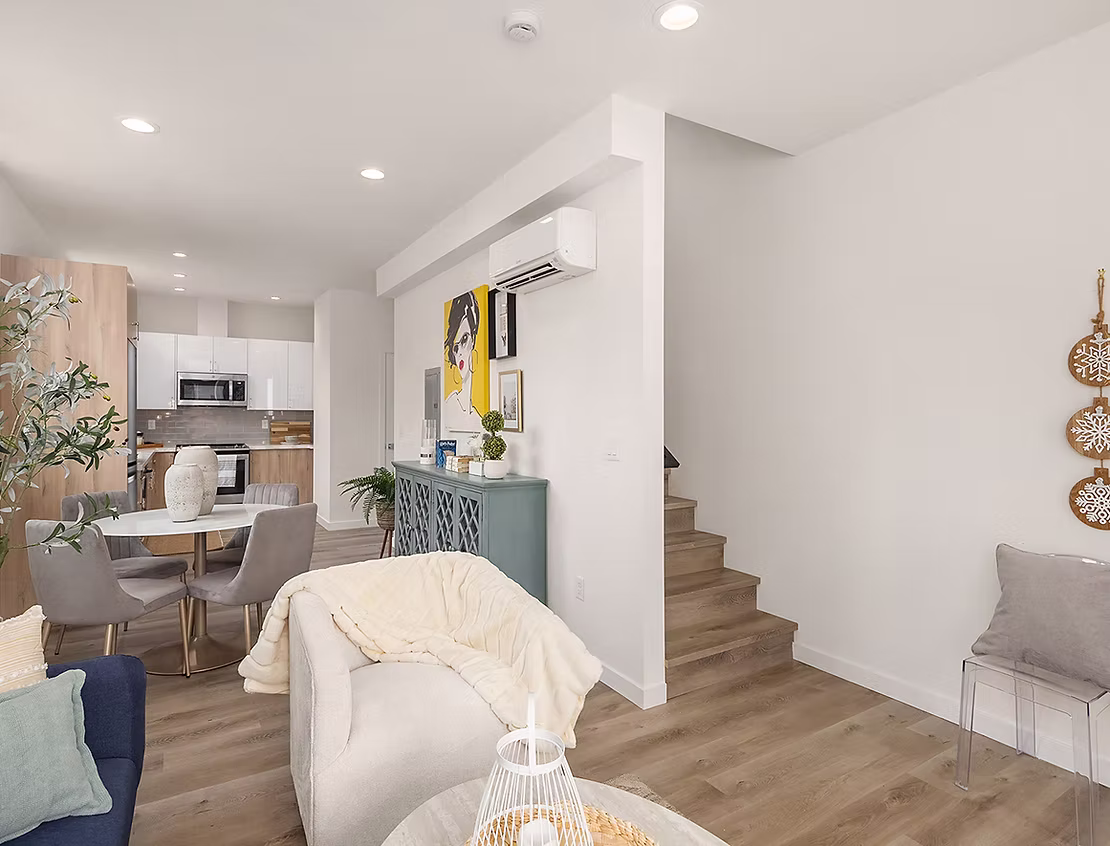 An open-concept living room and kitchen, featuring modern furniture and a staircase, illustrating a stylish and well-designed interior.