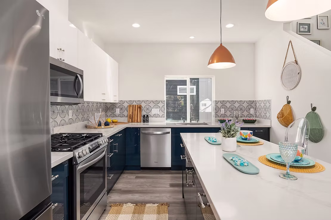 A brightly lit kitchen with a stylish blue and white color scheme, a unique backsplash, and a central island, demonstrating a premium interior design.
