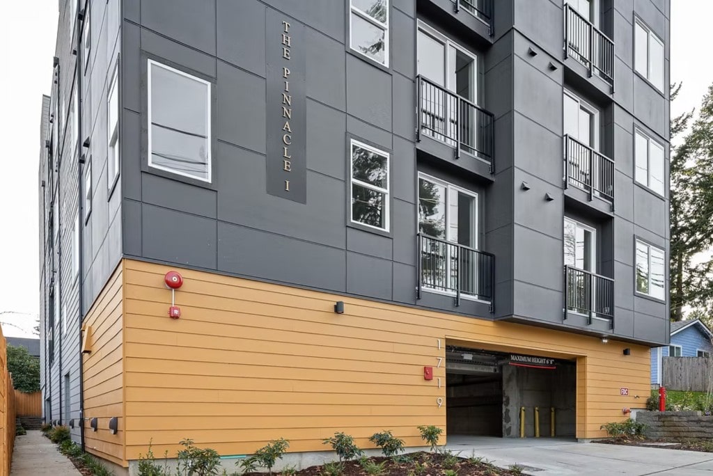 A close-up view of the entrance and lower facade of 'The Pinnacle I' apartment building, highlighting the modern design and property name. 