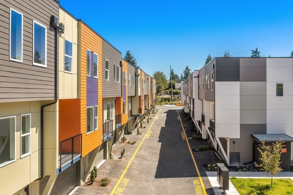 A street view of a new residential community featuring a variety of modern townhomes with multi-colored siding, built exclusively by TP Home in Washington.