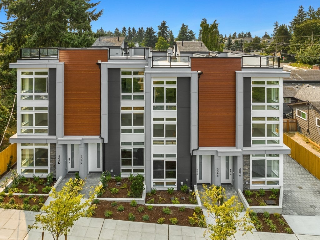 An aerial front view of modern townhomes with large windows and wood accents, highlighting the multi-story design of the ADHG developments in Washington.