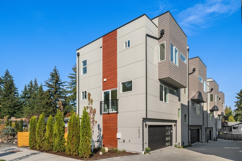 A block of newly completed modern townhomes with gray and wood-look paneling, showcasing the contemporary residential architecture built by ADHG and TP Home.