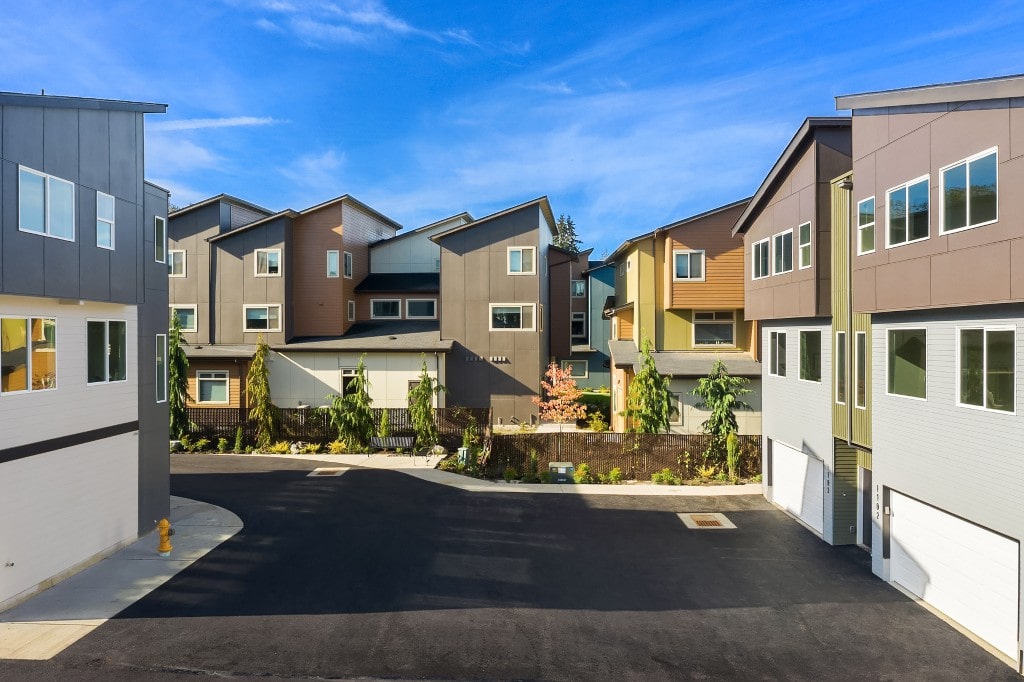 A street view of a new townhouse development in Monroe, showing a variety of modern home designs and exterior finishes.