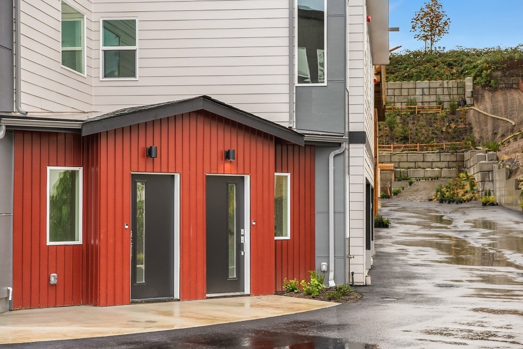 The modern red-sided entrance of a townhouse, featuring a clean design and two separate doors, highlighting a unique exterior finish.