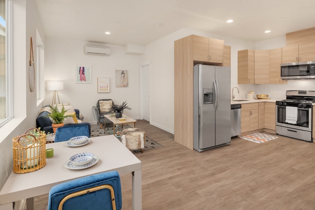 A bright open-concept living area and kitchen with light wood-tone cabinets, highlighting a modern interior design.