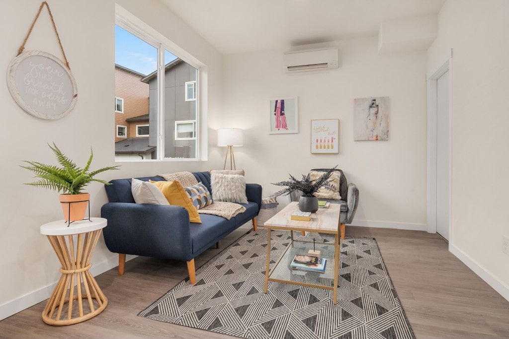 A modern living room with a navy blue sofa, a glass coffee table, and minimalist artwork, showcasing a comfortable and stylish apartment interior.