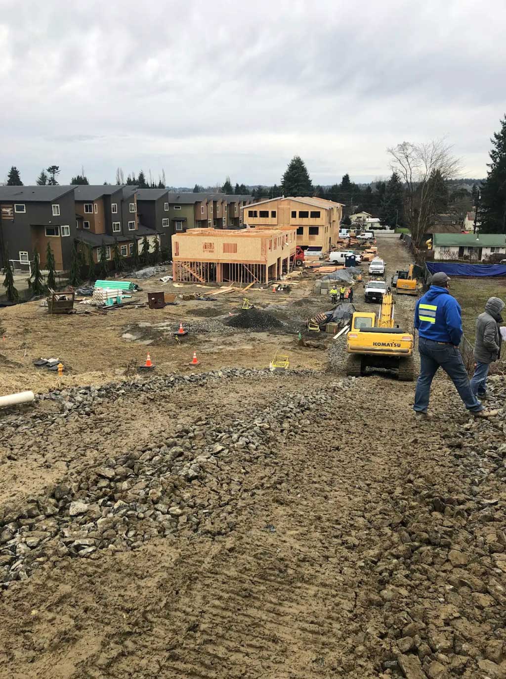 A panoramic view of a townhouse development under construction, showing framing, heavy equipment, and workers on site.