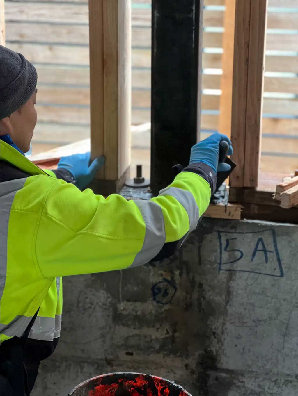 A construction worker installs a wooden frame on a concrete foundation, highlighting the hands-on work in the development process. 