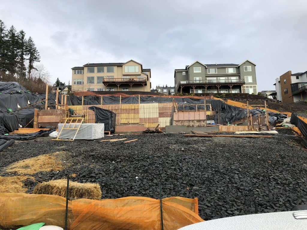 A hillside construction site showing ongoing excavation and soil stabilization work, essential for ADHG's challenging developments.