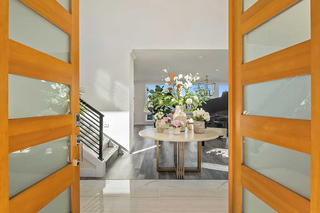 The grand entryway of a Bellevue home, featuring large wooden doors and a luxurious tiled floor, showcasing the premium finishes from Oscar Surfaces.