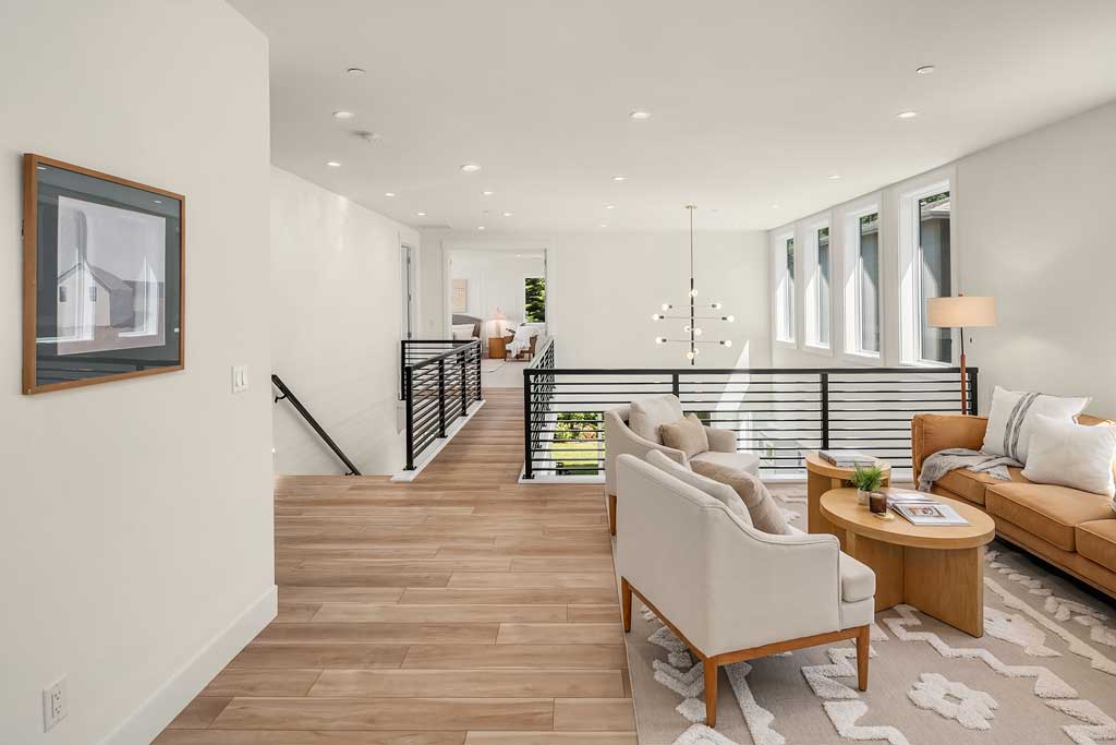 A spacious living room with an open lofted floor plan, modern furniture, and a staircase, highlighting the airy feel of the home's design.