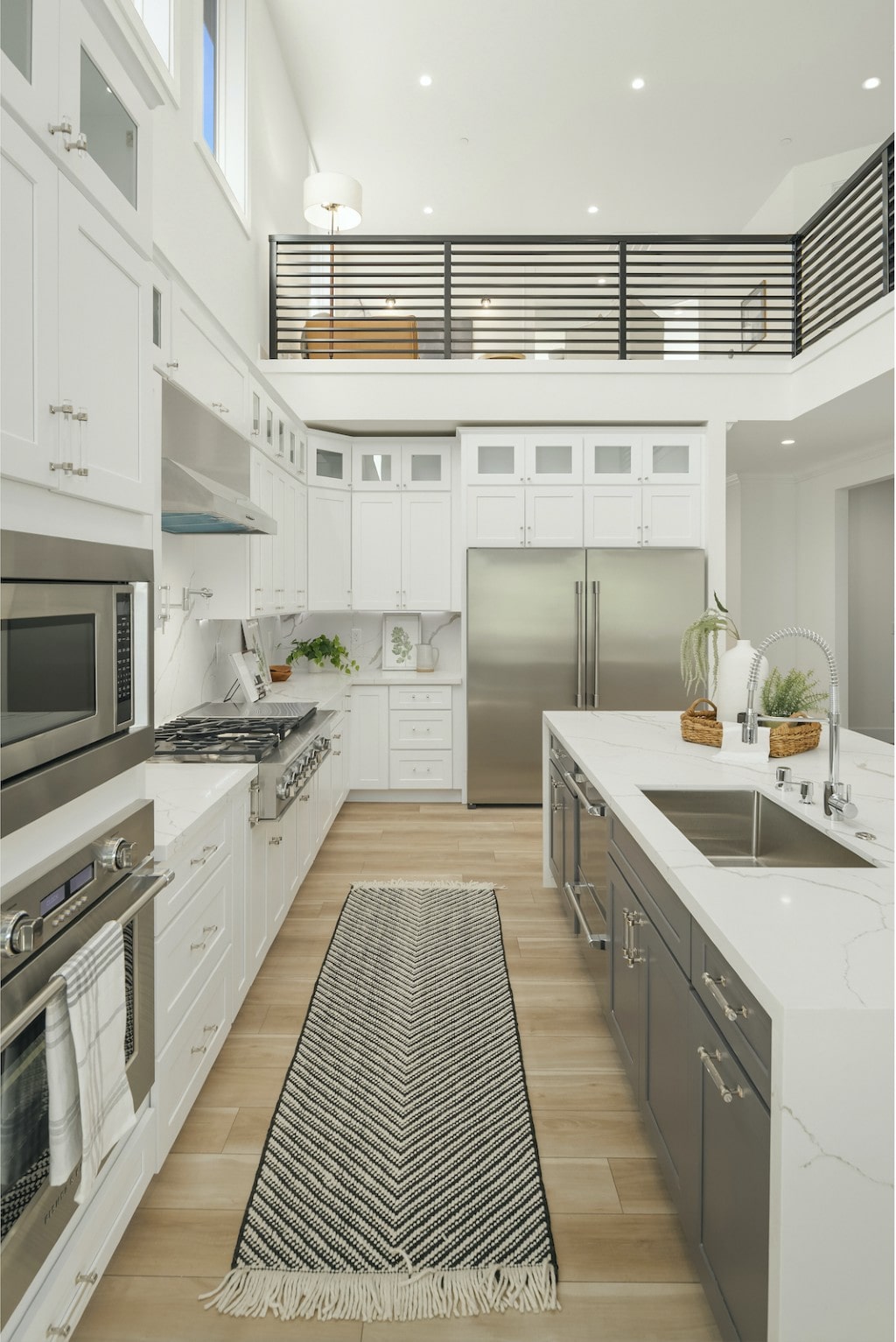 A close-up of a modern kitchen with a large island, stainless steel appliances, and a detailed runner rug, highlighting the high-quality surfaces from Oscar Surfaces.